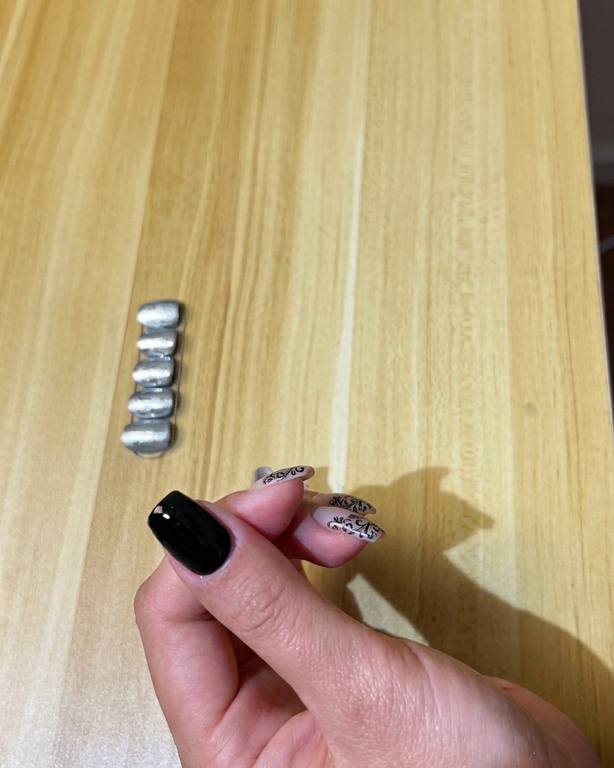 A brush applying a smooth coat of black gel polish to a natural nail.