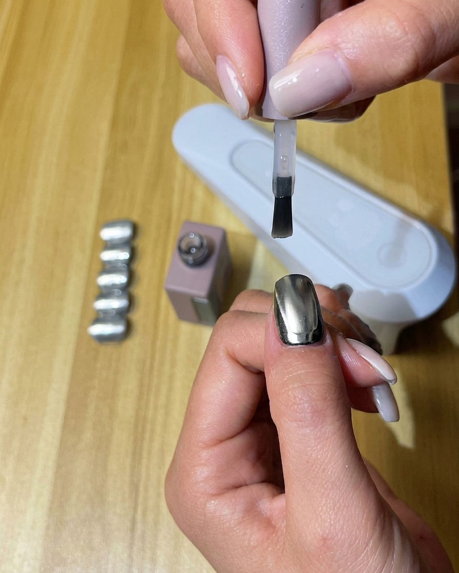 A hand with nails coated in matte top coat curing inside a UV/LED nail lamp.