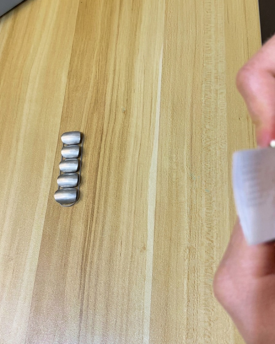A lint-free wipe being used to clean the surface of a matte-finished nail.