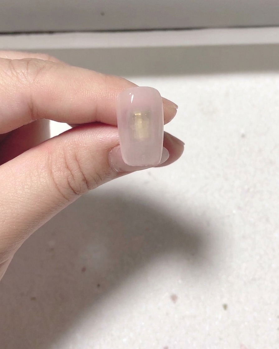A manicured nail positioned inside a professional nail lamp for curing.