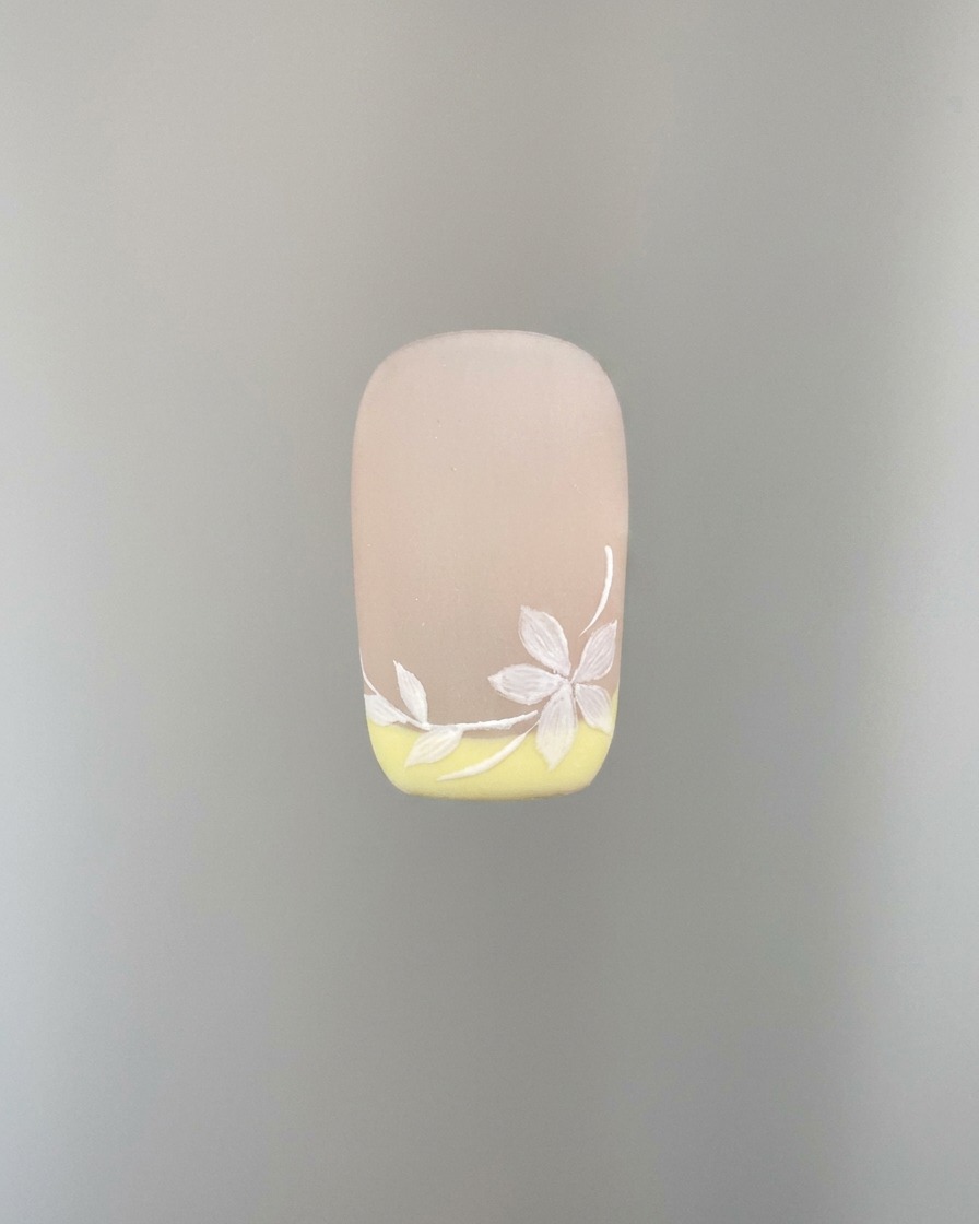 A detailed shot showing additional white sakura flower petals being added to the nail art.
