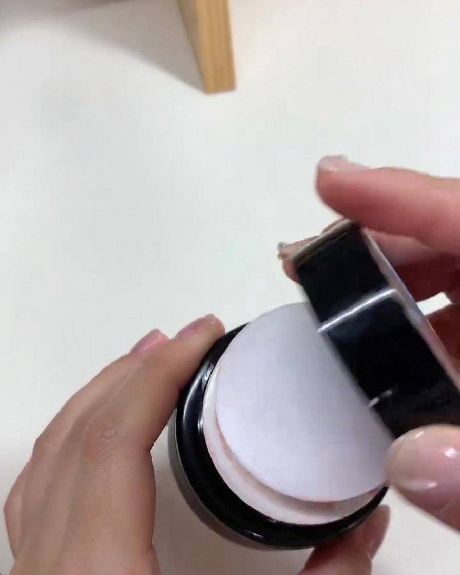 A brush applying a smooth layer of nude gel polish onto a nail extension tip.