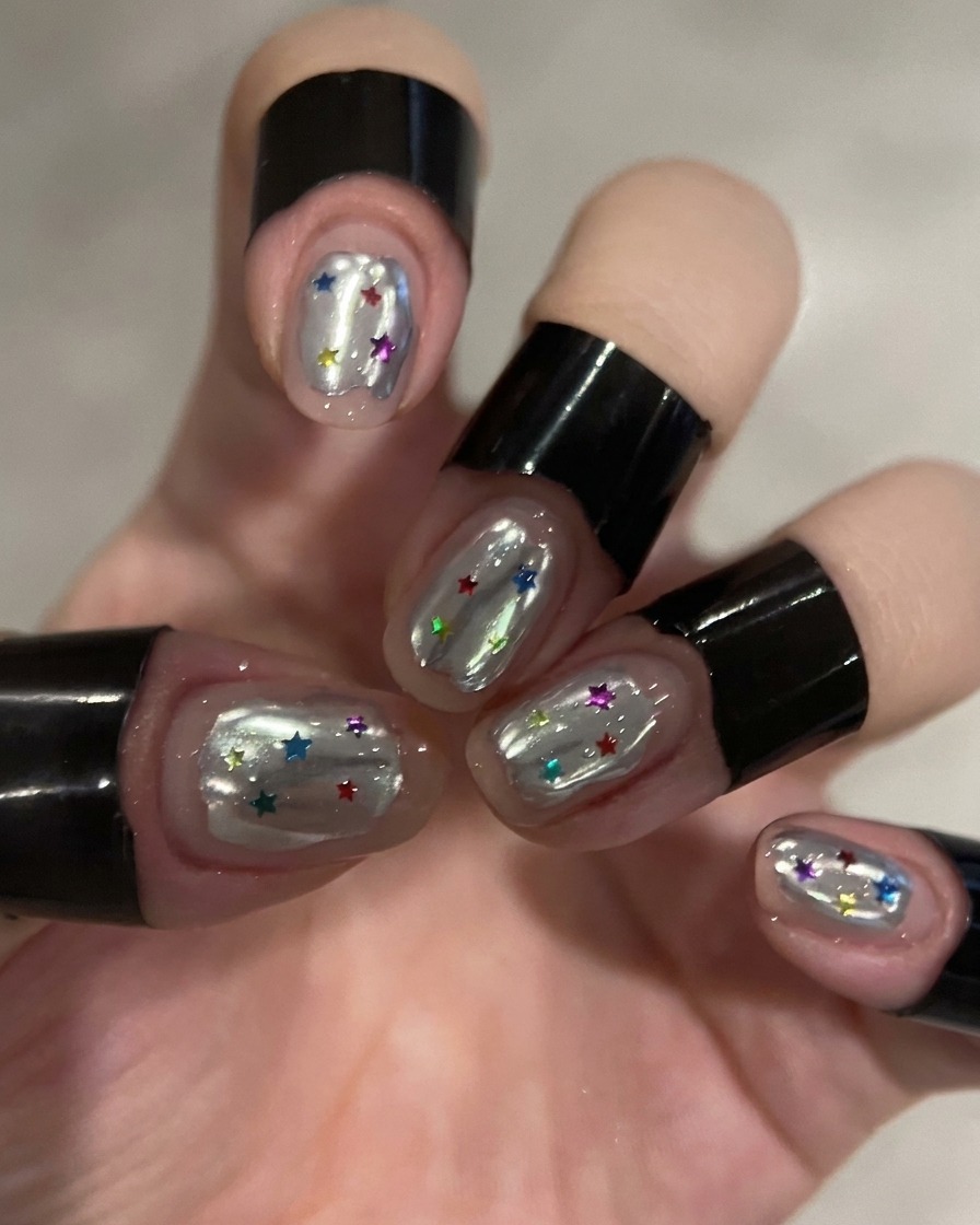 A small sponge being used to remove excess silver chrome powder from a nail.