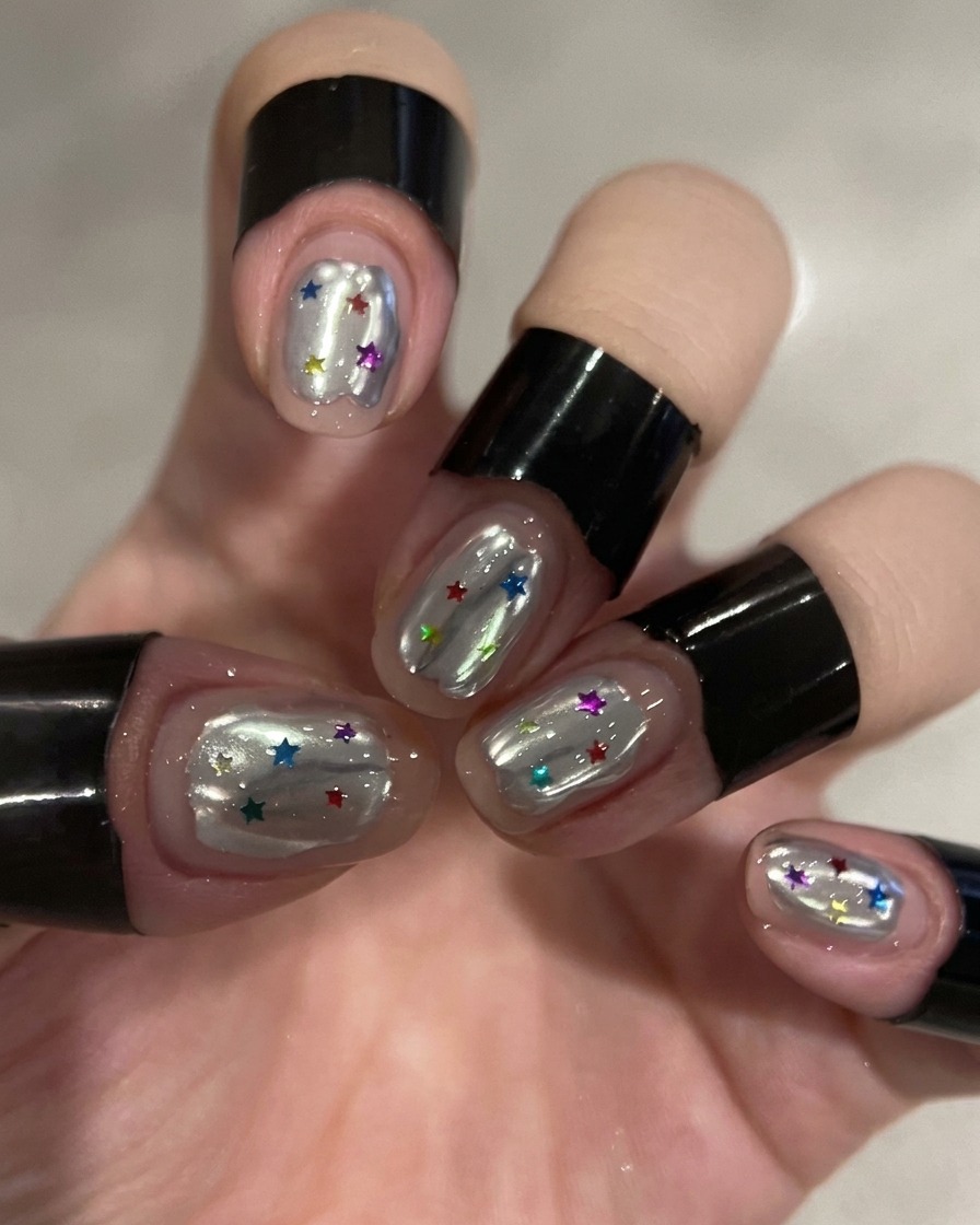 A brush applying a clear top coat over a silver chrome nail.