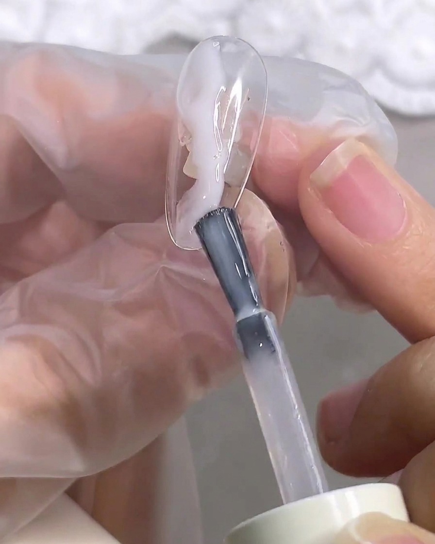 A close-up of a brush smoothing out the blooming gel on the nail surface.