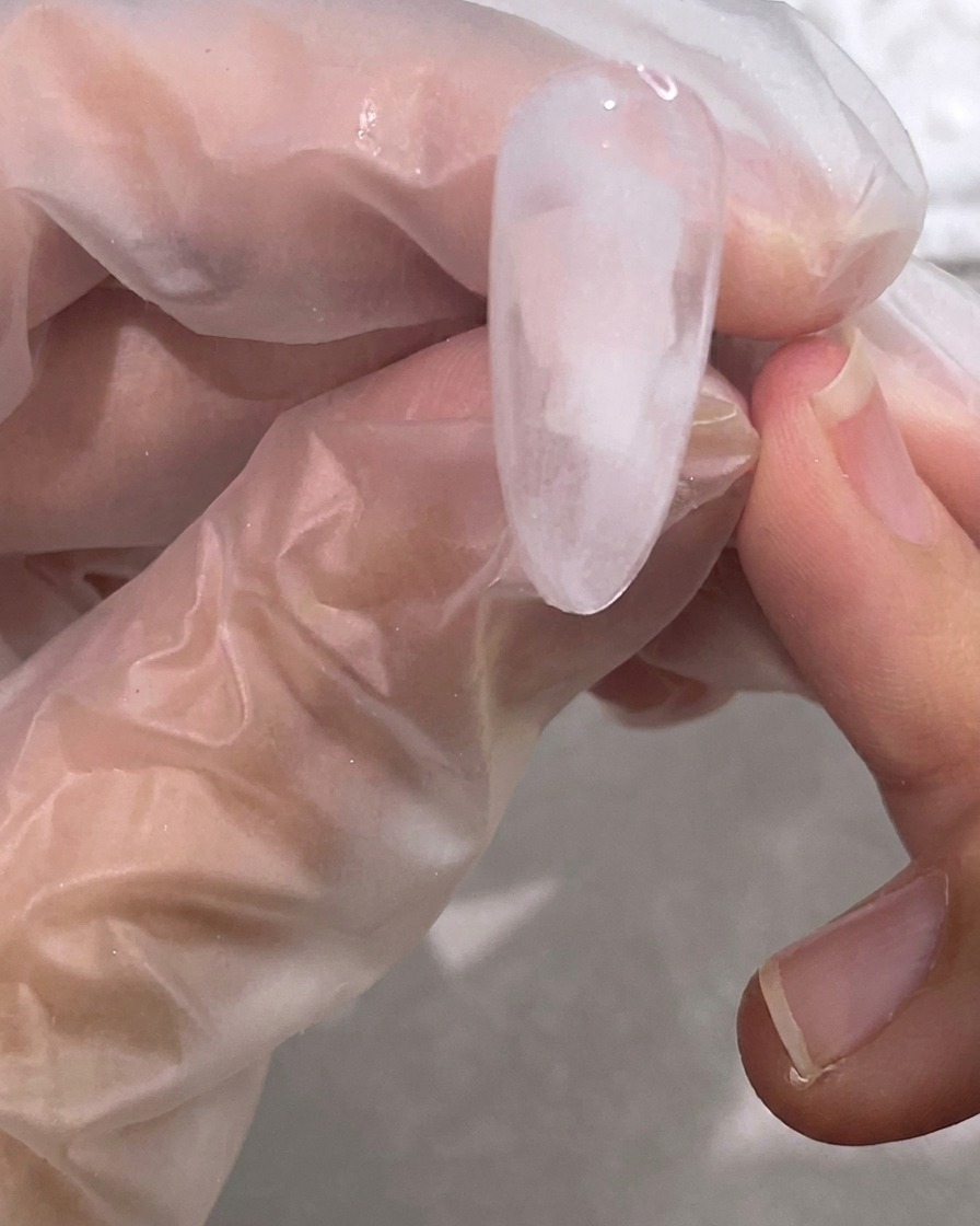A brush blending the white gel into the clear base to create a soft, cloudy marble effect.