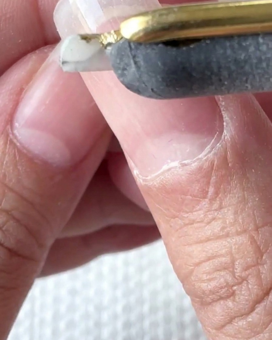 A brush applying a clear liquid layer over the nail.
