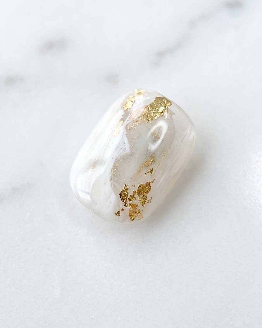 Close-up of a fine liner brush adding precise, thin white details to a marble-patterned nail.