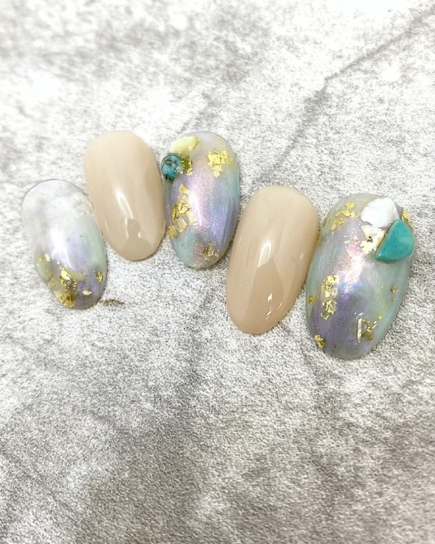 A close-up view of a hand with the completed marble and gold foil nail art curing inside a professional UV/LED nail lamp.