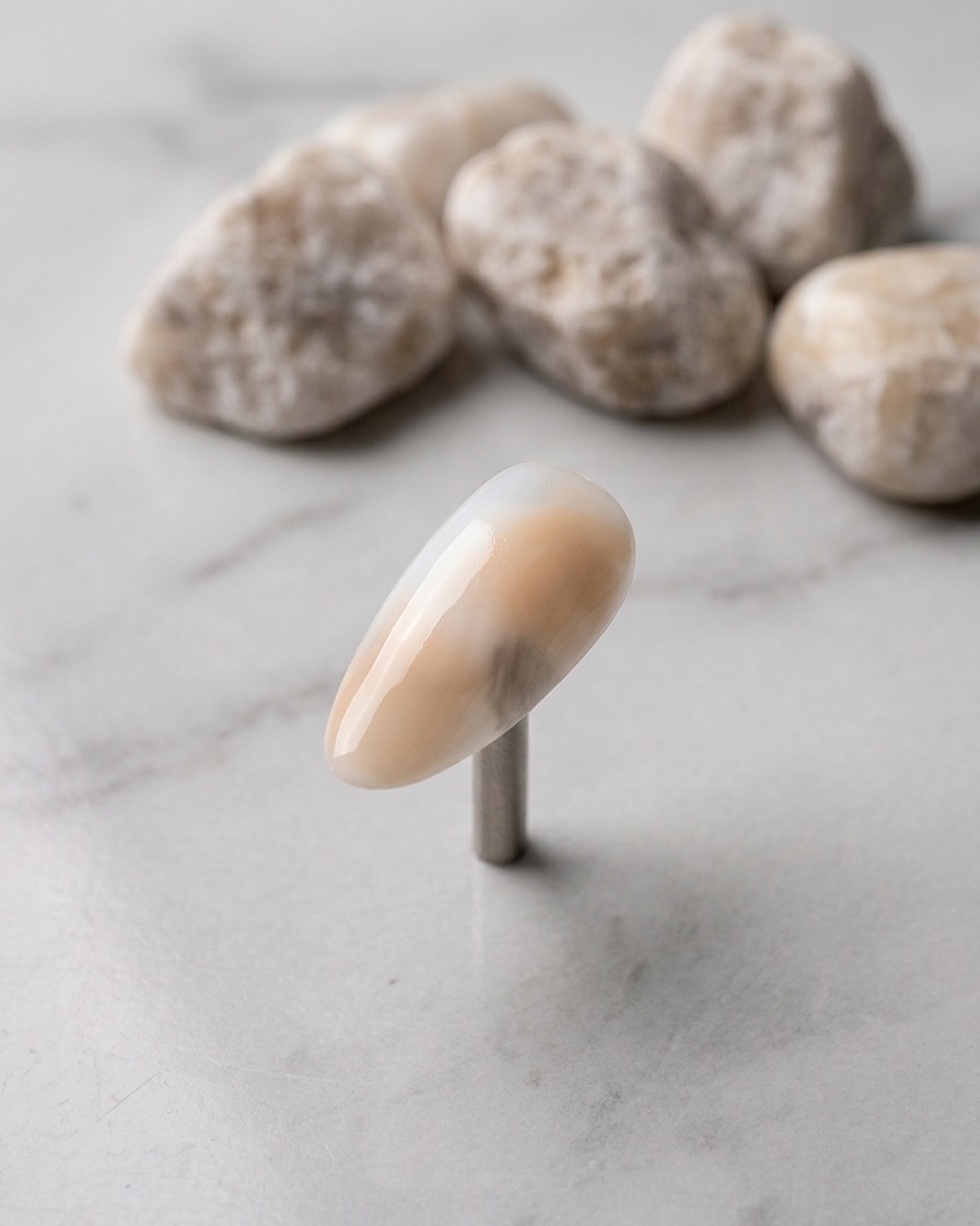 A close-up of a nail with a gray gel dab applied to the lower left section.
