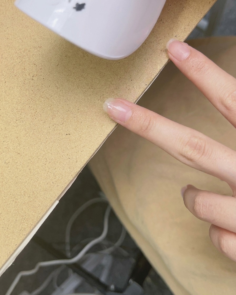 A handheld UV/LED lamp hovering over a fingernail to cure the polish.