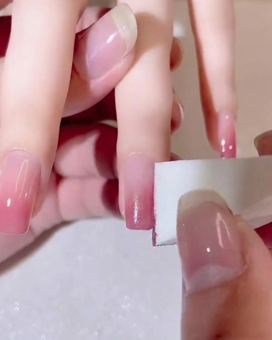 A sponge gently blending the color transition on a fingernail.