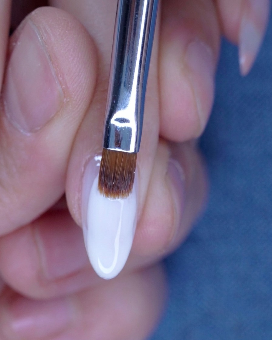 Blending the second layer of nude gel with a brush for a seamless transition.