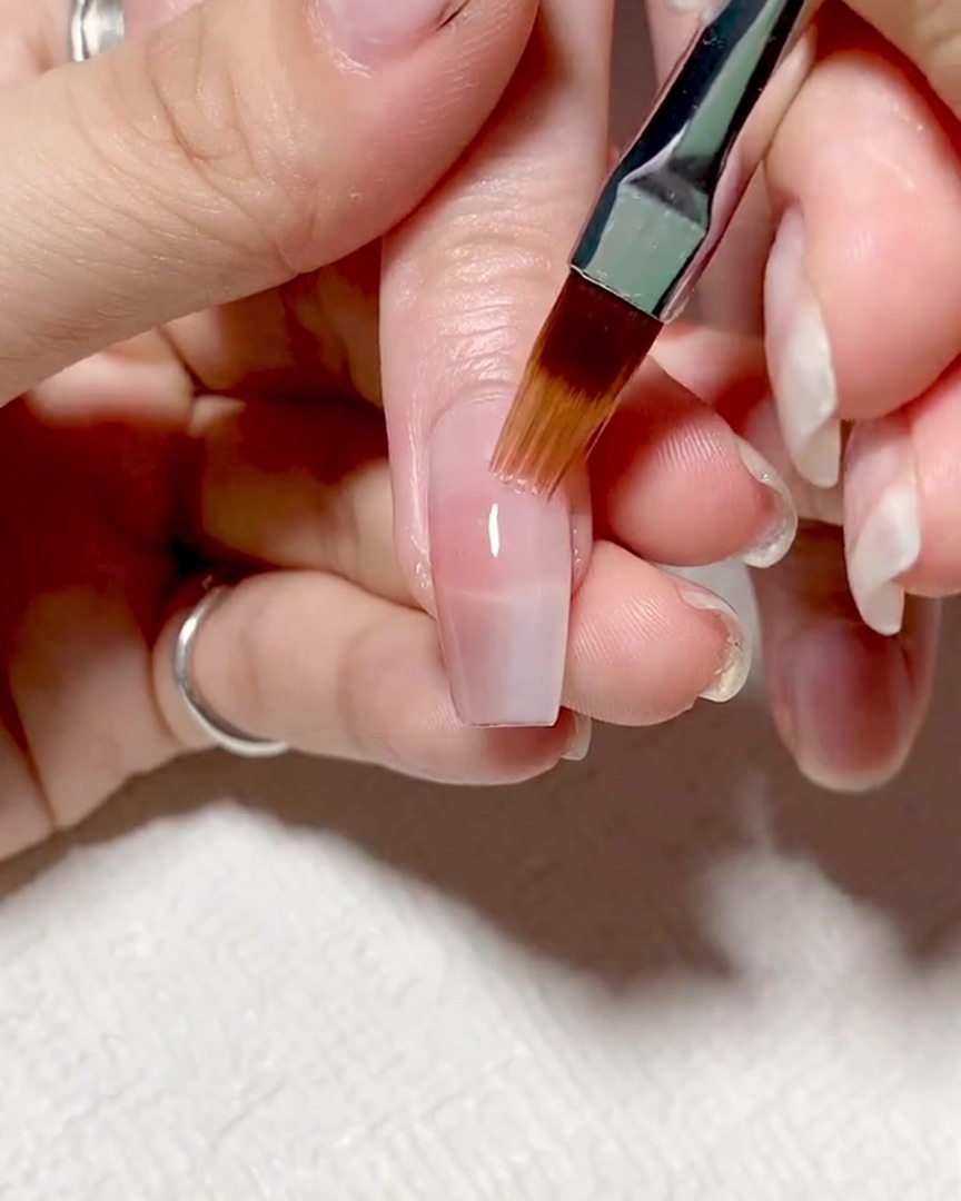 A specialized gradient brush blending the meeting point of two gel colors on a nail.