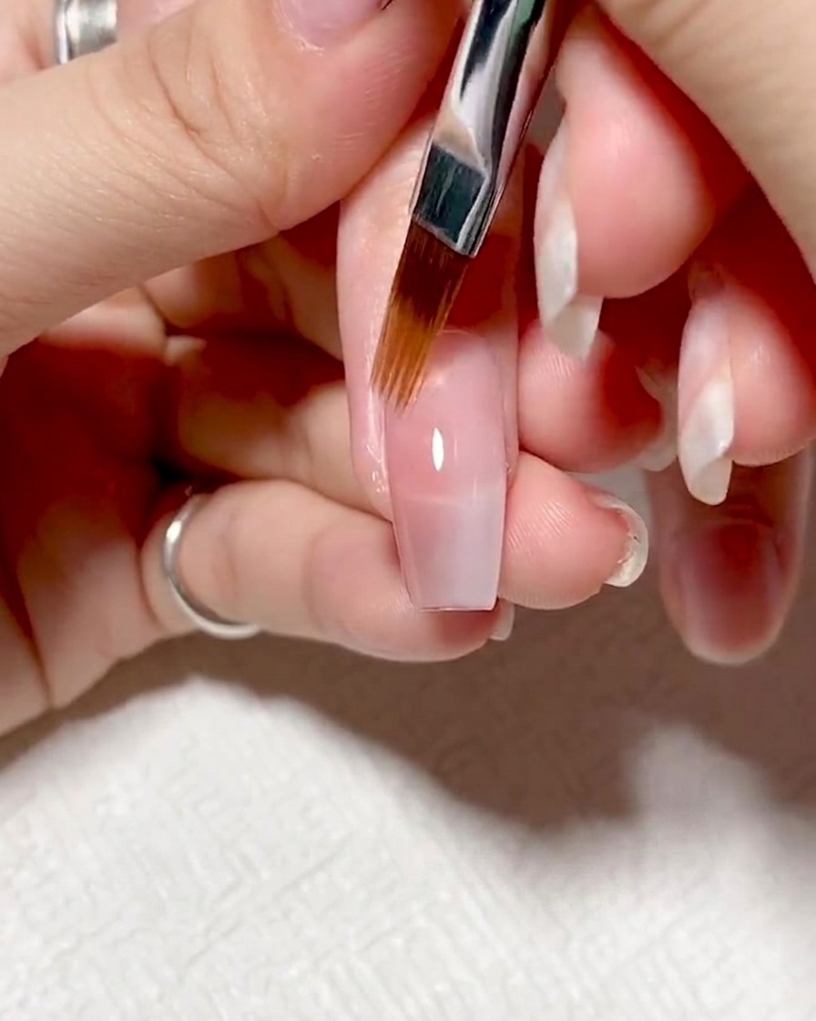 Nails inside a UV/LED lamp curing under purple light.
