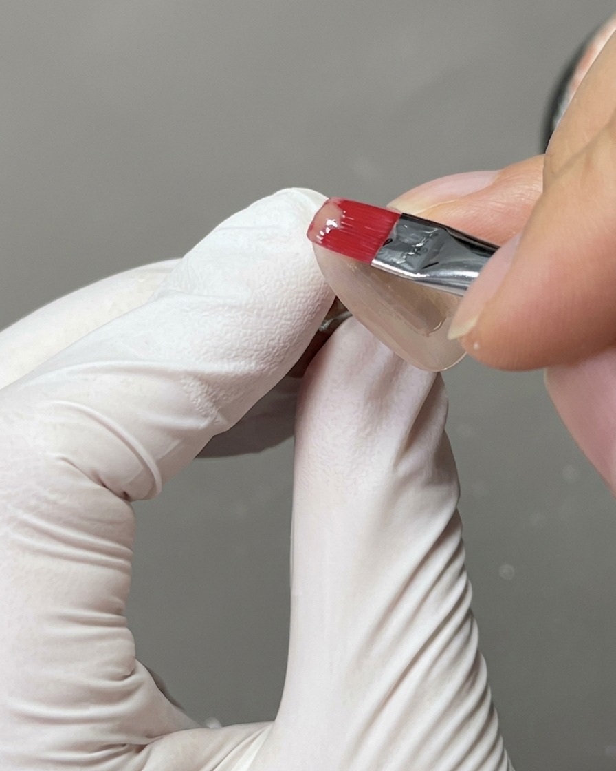A nail tip placed inside a UV nail lamp for the curing process.