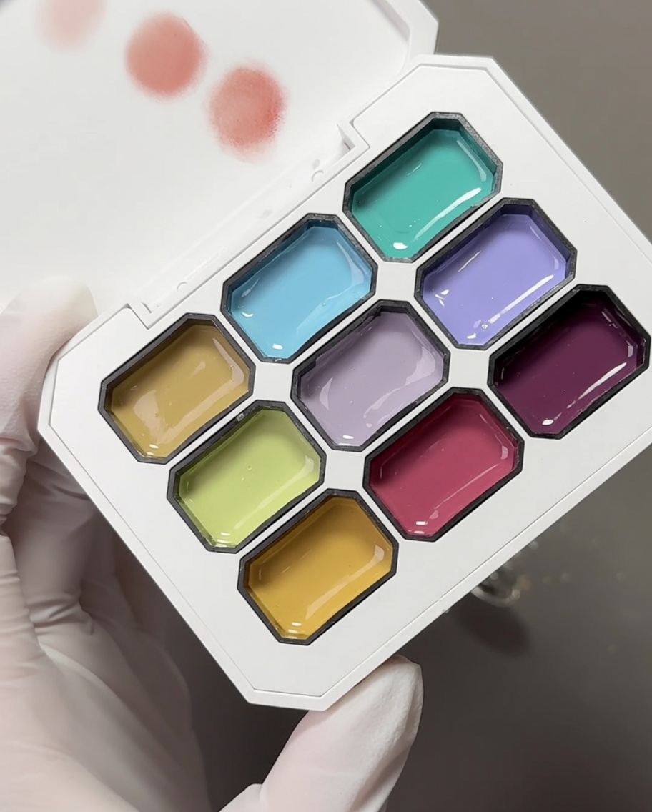 A palette with multiple pastel gel colors and a makeup sponge used to pick up the pigments.