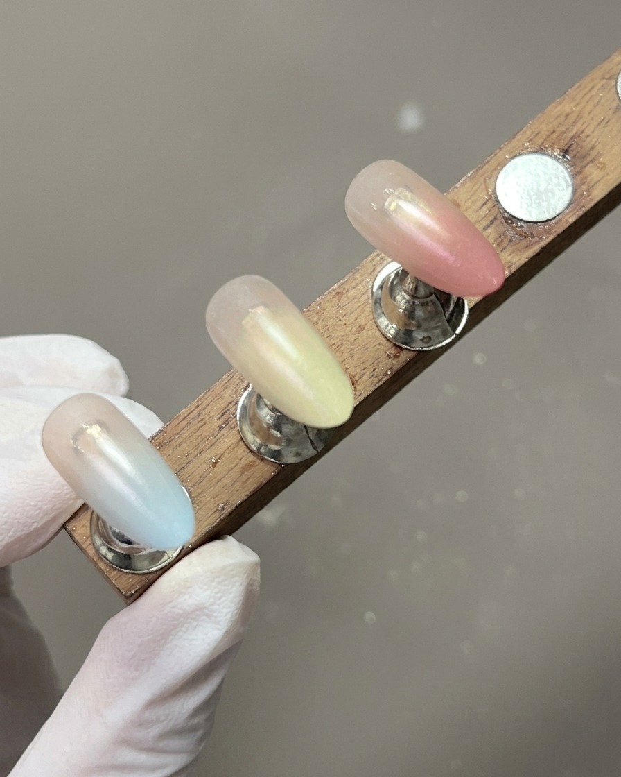 A display stand showing nail tips with completed, soft pastel gradients.