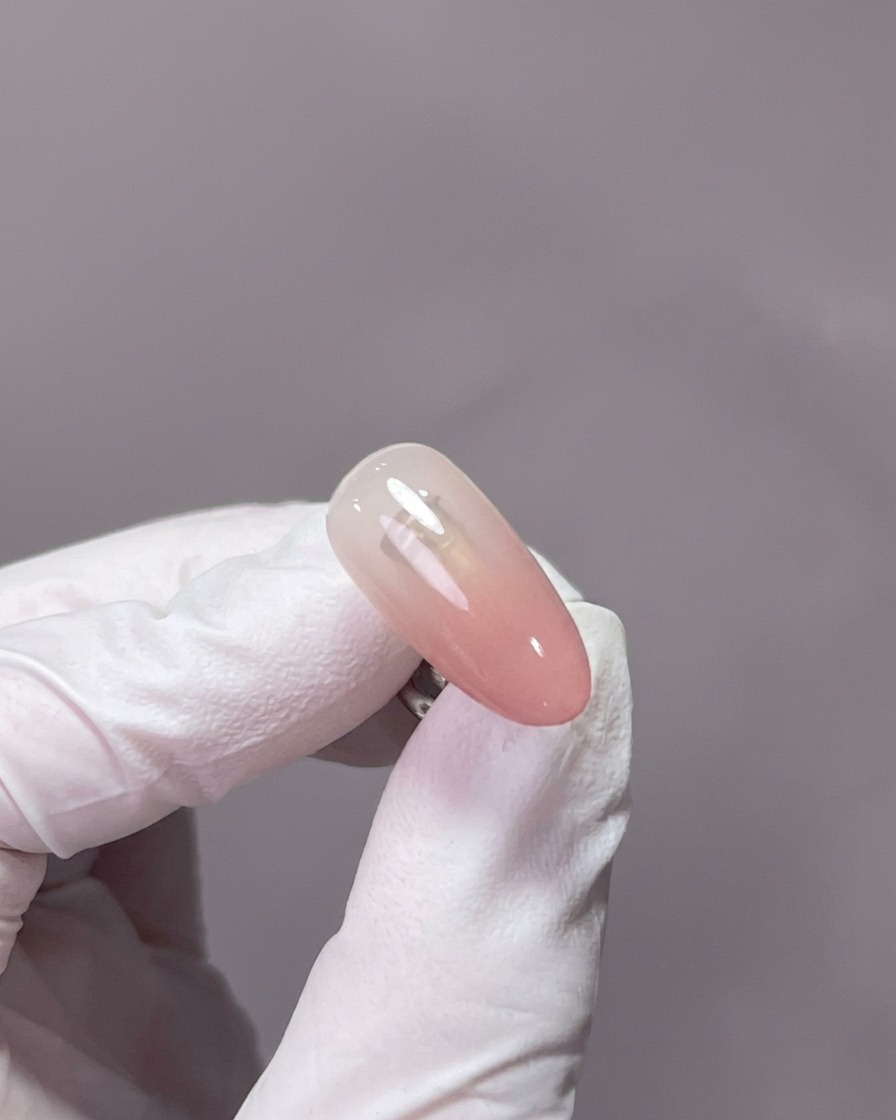 A close-up of a hand resting inside a professional UV/LED nail lamp, with the gel-covered nails centered under the light.