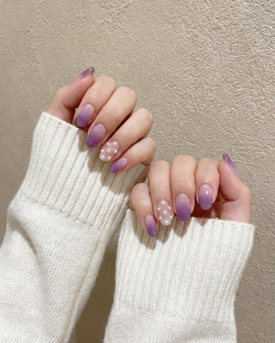 A small detail brush dabbing a concentrated dark purple gel onto the tip of a light purple painted nail.