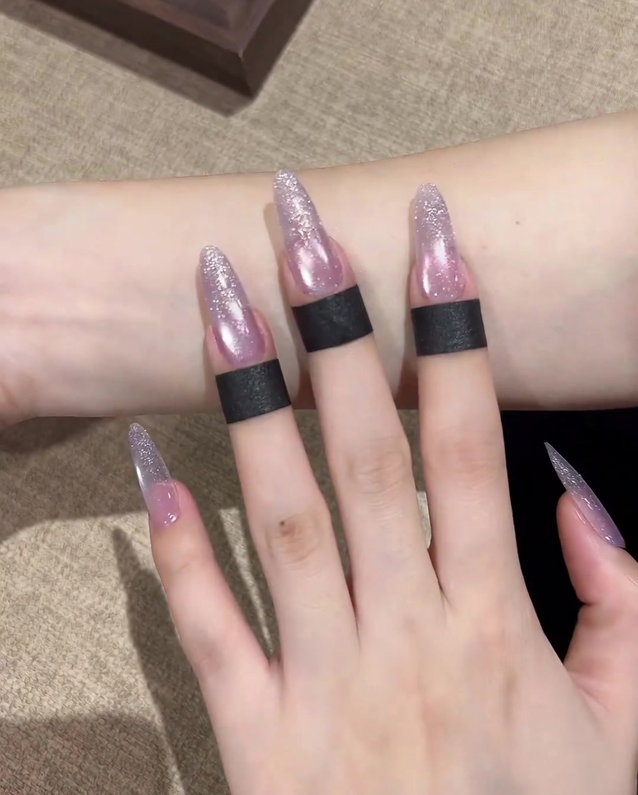 A close-up of a brush applying a clear base coat gel onto a clean, prepared natural nail.