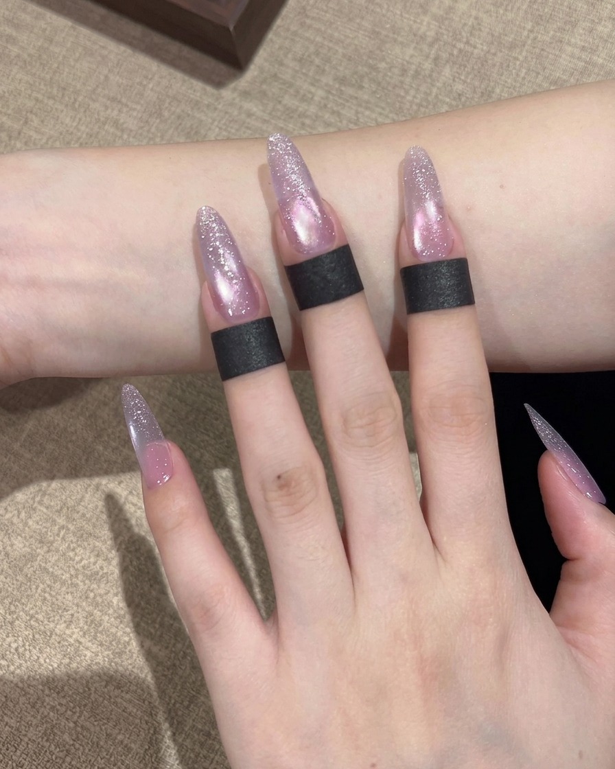 A brush applying a shimmering purple-toned cat eye gel polish over the entire surface of the nail.