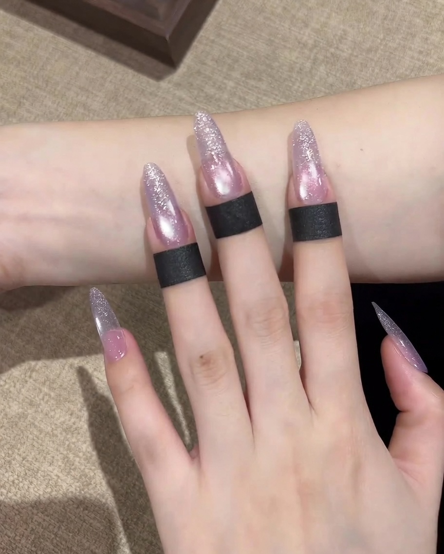 A magnet positioned horizontally over the nail, being drawn across to shift the magnetic cat eye pigment.