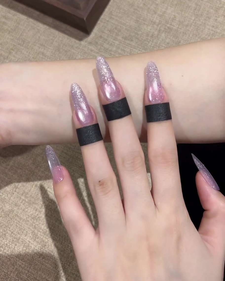 A close-up showing the magnet being used to gather the shimmering particles into a circular highlight in the center of the nail.