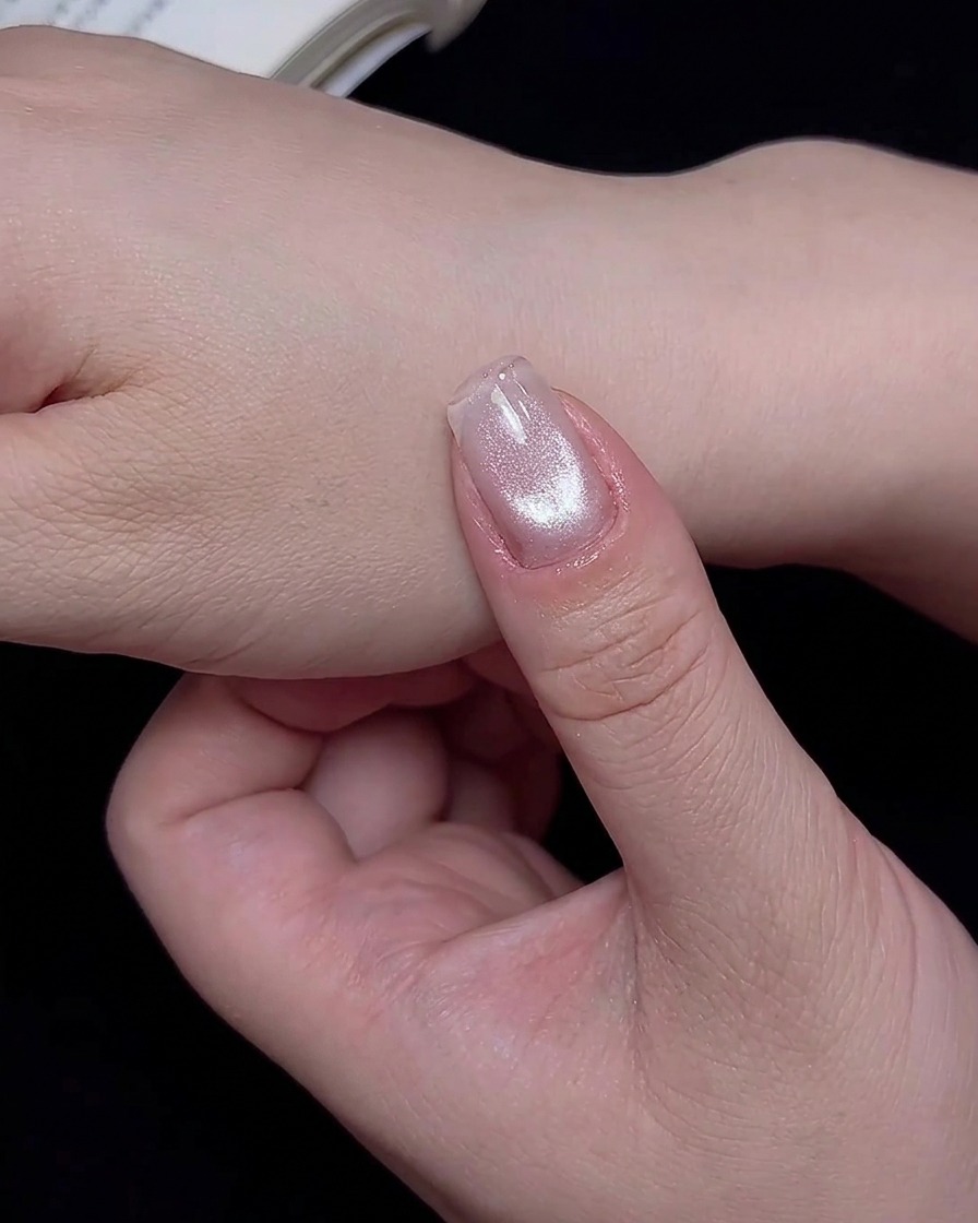 A fingernail placed inside a UV/LED lamp to cure the freshly applied cat-eye design.
