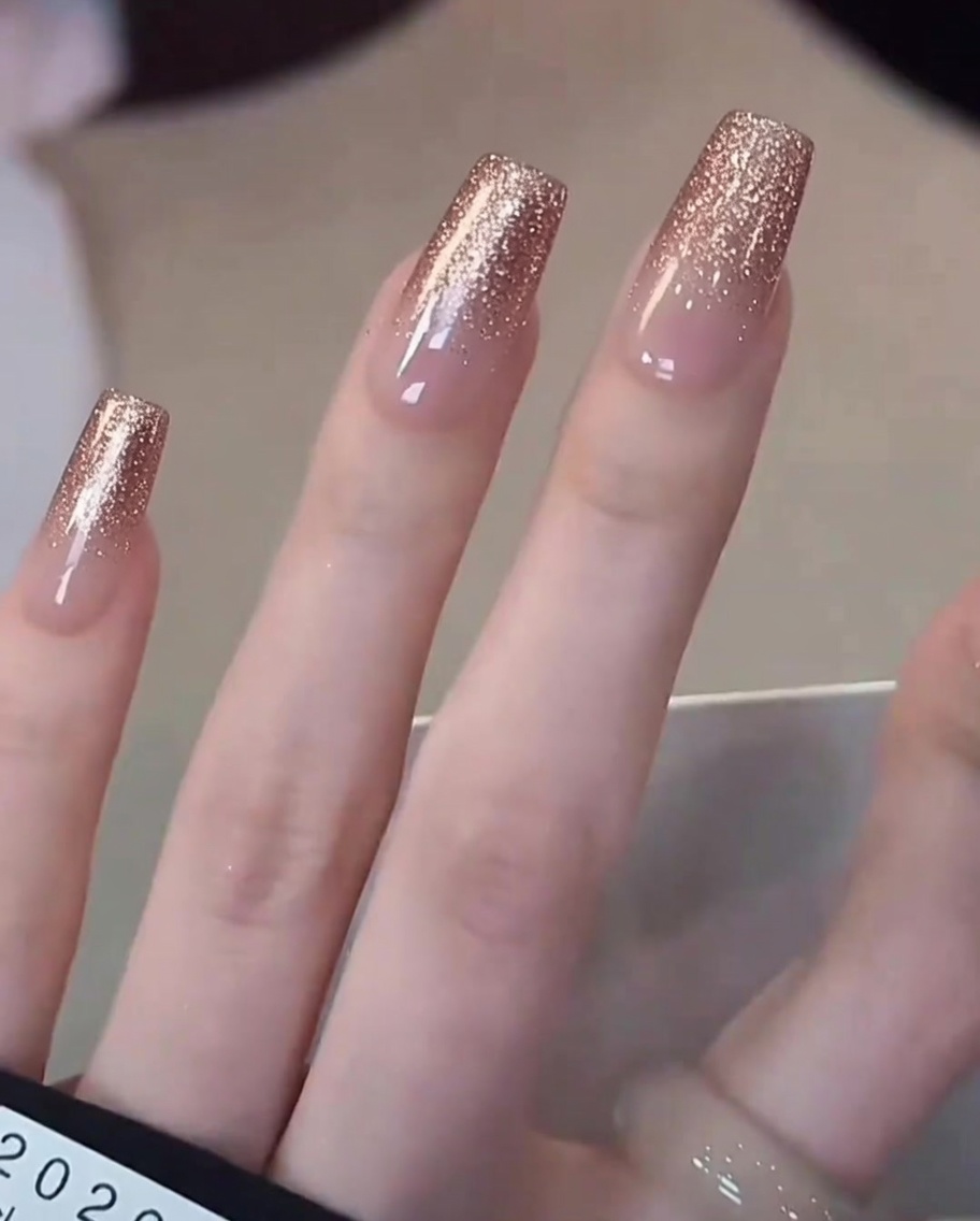Close-up of a brush applying milky white gel polish focused on the tip of a natural nail.