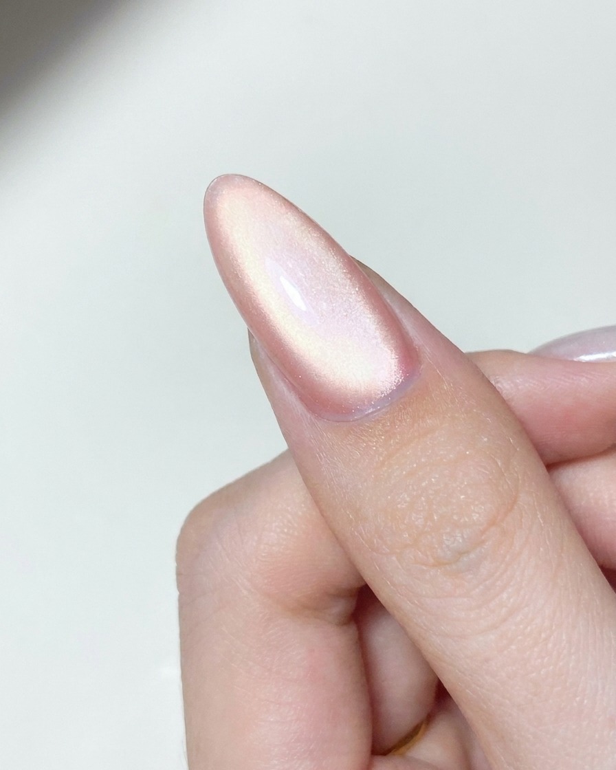 An applicator tool buffing shimmering aurora chrome powder onto a cured gel nail surface.
