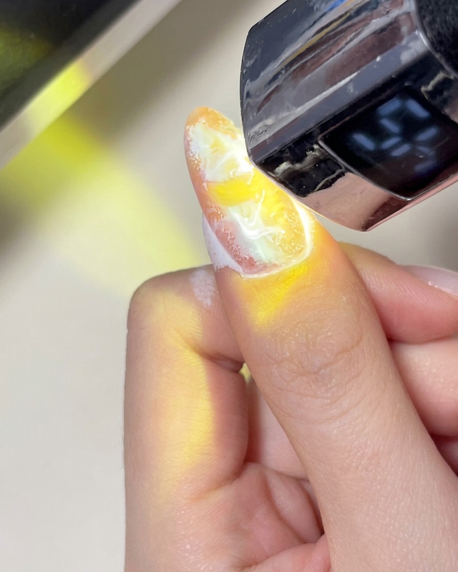 A soft, fluffy brush being used to gently sweep dust off a manicured nail surface.