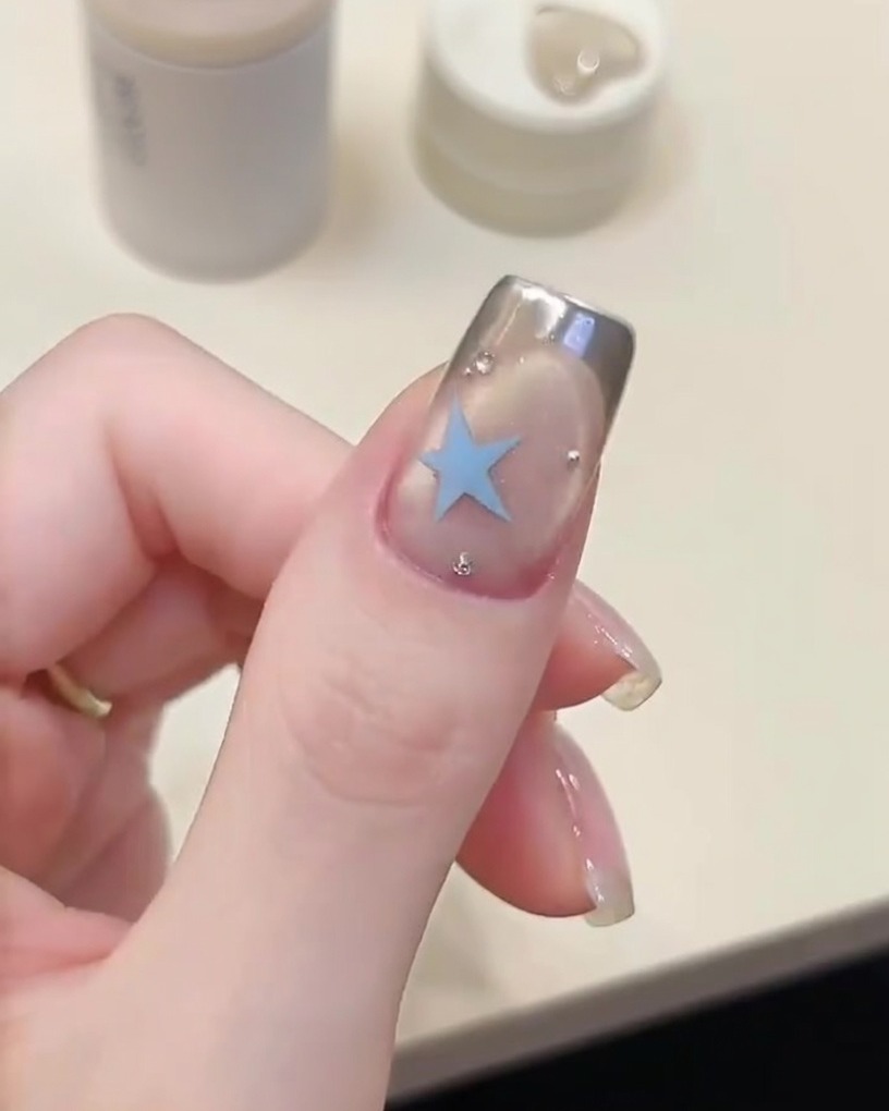 A brush applying a clear gel base coat to a prepped nail plate.