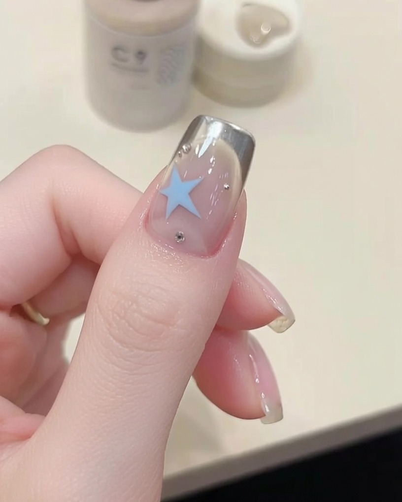 A nail brush applying a clear, glossy top coat over a manicured fingernail.