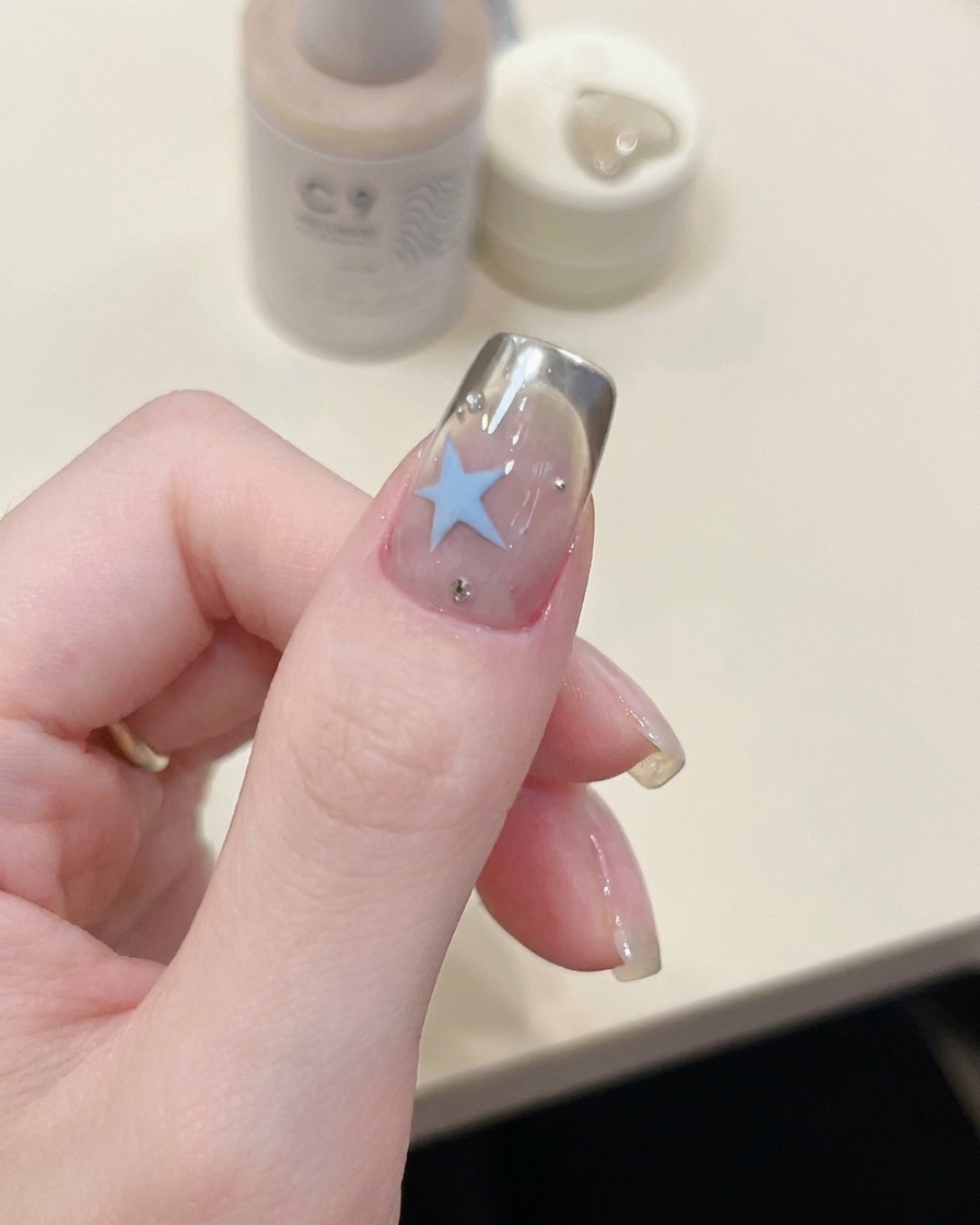 A pair of tweezers placing a curved French tip stencil onto the tip of a fingernail.