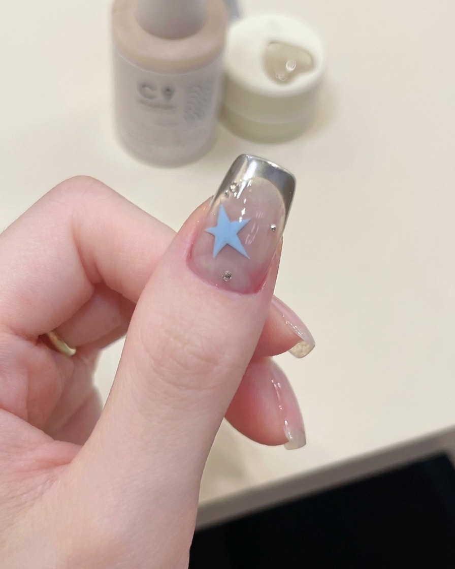 A top coat brush applying a clear, glossy layer of gel over the finished nail art.