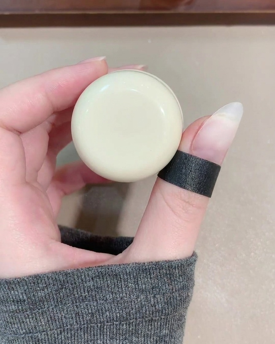 A gel brush applying a sheer, shimmering blue-toned cat eye gel onto a fingernail.