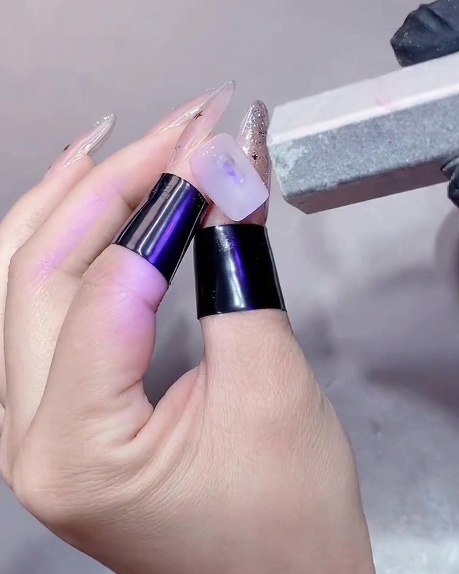 A close-up of a nail being buffed with a block buffer to smooth the surface.