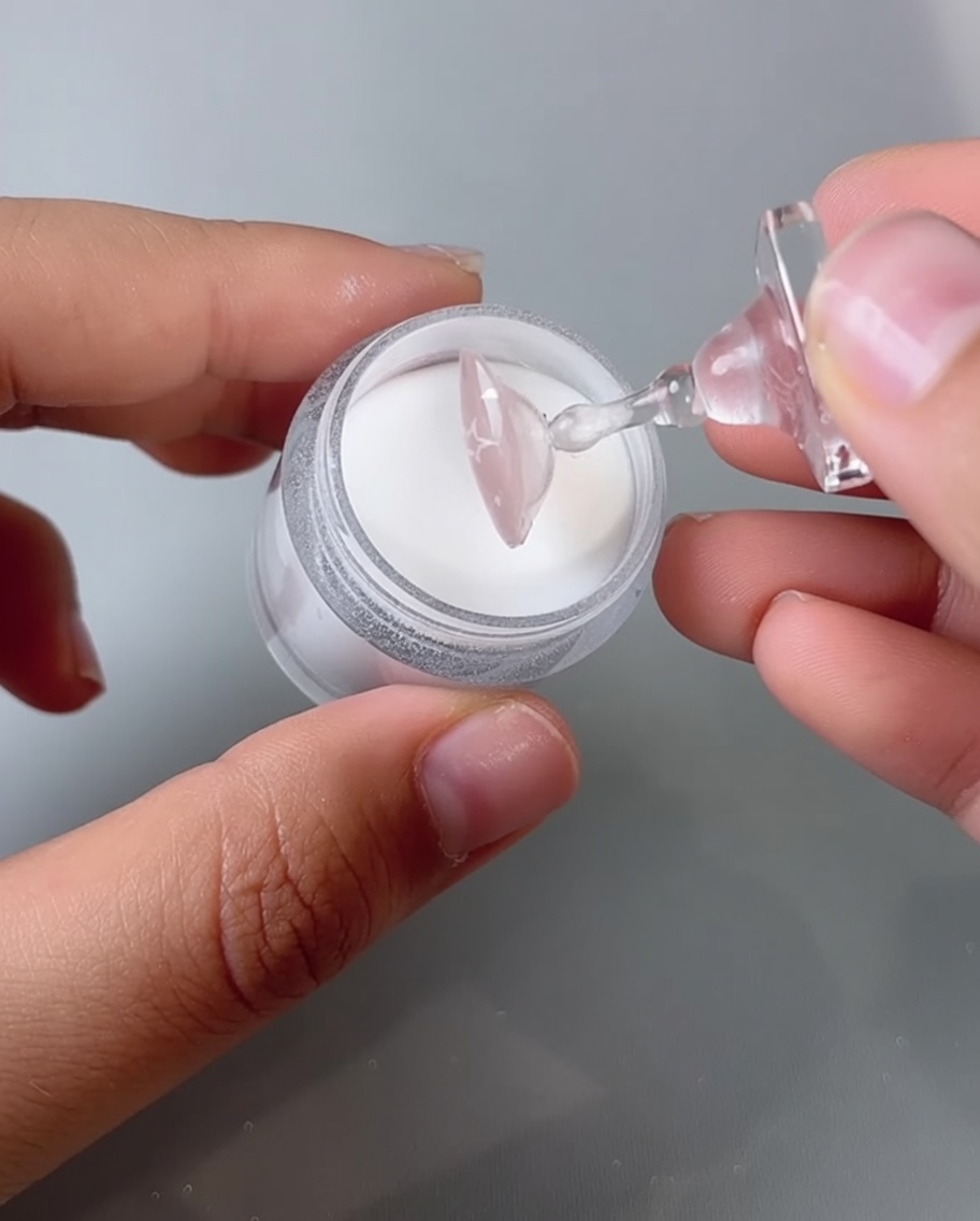 A fingernail being placed inside a UV/LED nail lamp for curing.