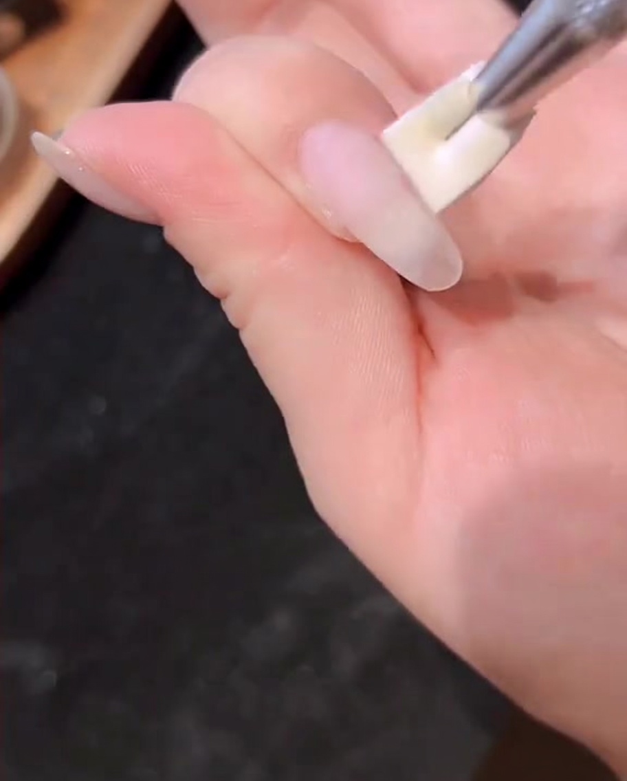 A hand resting inside a professional UV/LED nail lamp with the light activated.