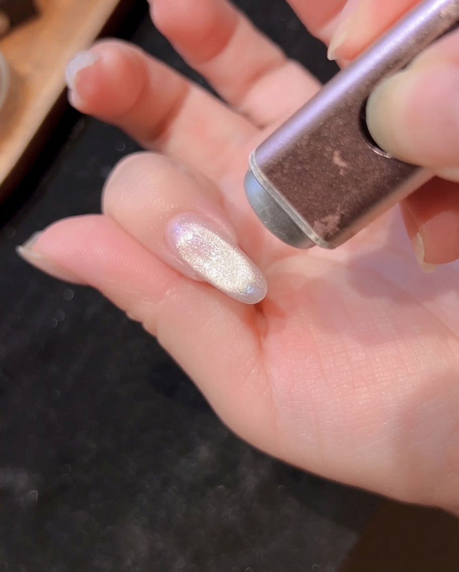 A close-up view of a hand inside a UV/LED nail lamp, with the nails receiving light to cure the gel polish.