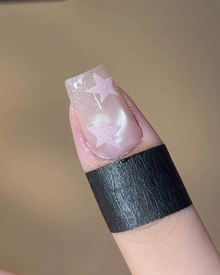 A brush applying a shimmering 05 cat-eye gel onto a clean nail plate.