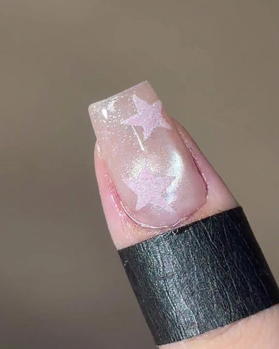A magnet tool held above the nail, causing the shimmering particles in the gel to form a glass-like bead.