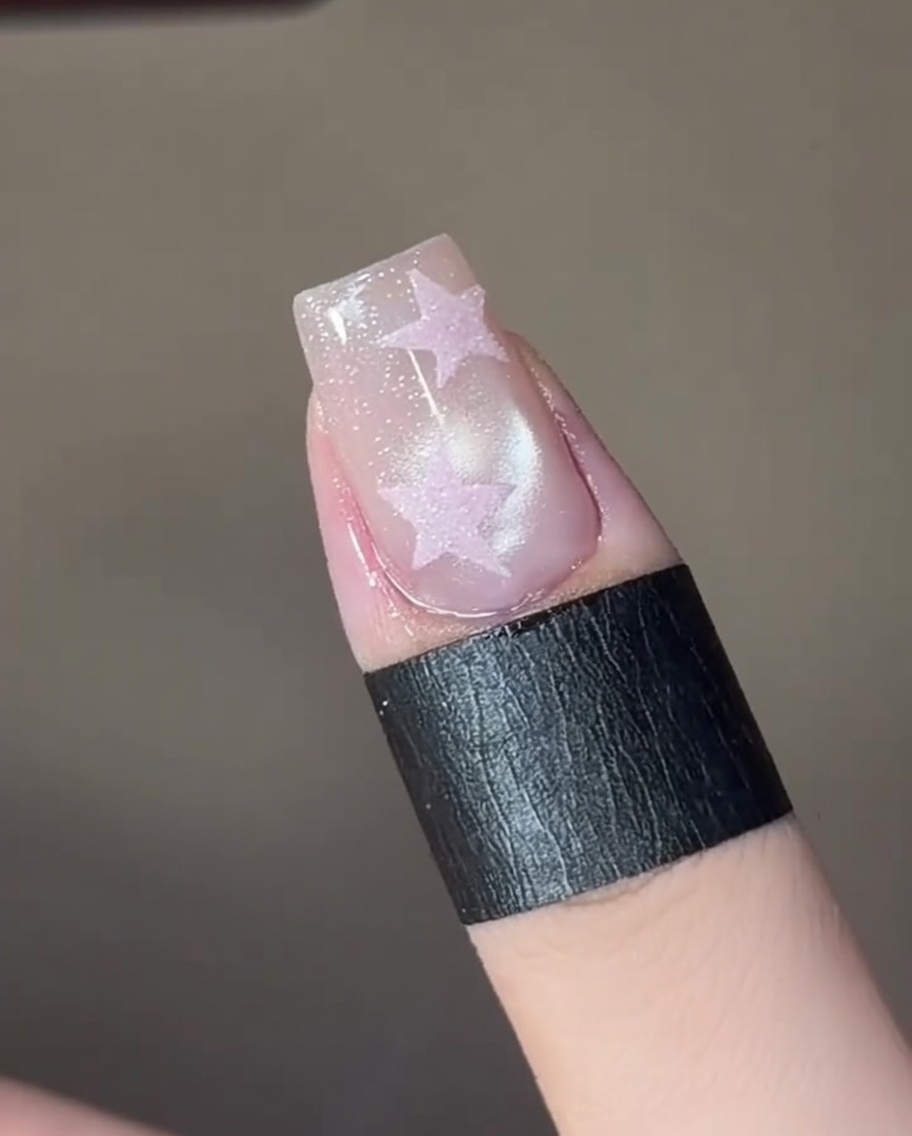 The nail under a mini LED lamp being cured after the cat-eye effect is set.