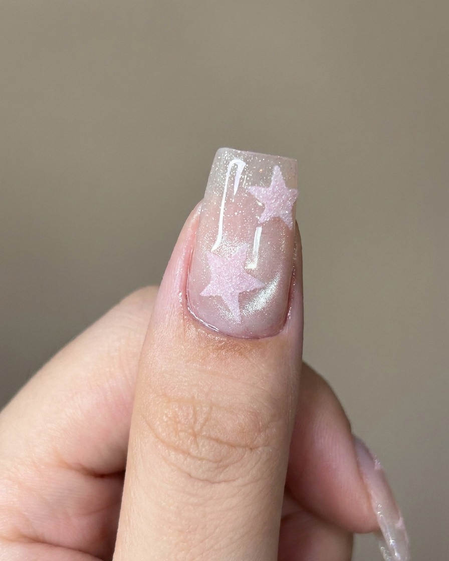 A brush applying a clear top coat over the shimmering cat-eye nail.