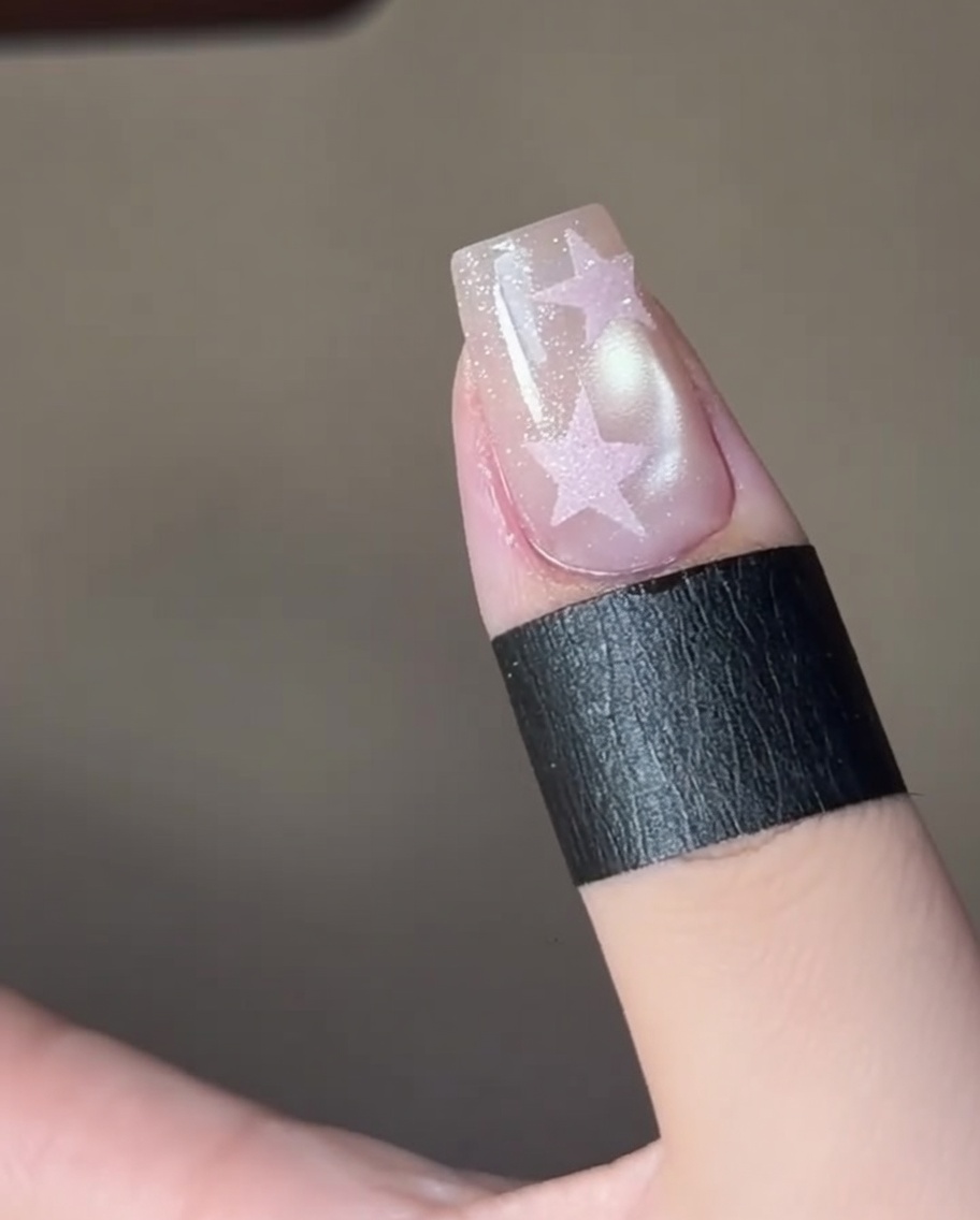 Fingers curing a star nail design under a professional UV nail lamp.