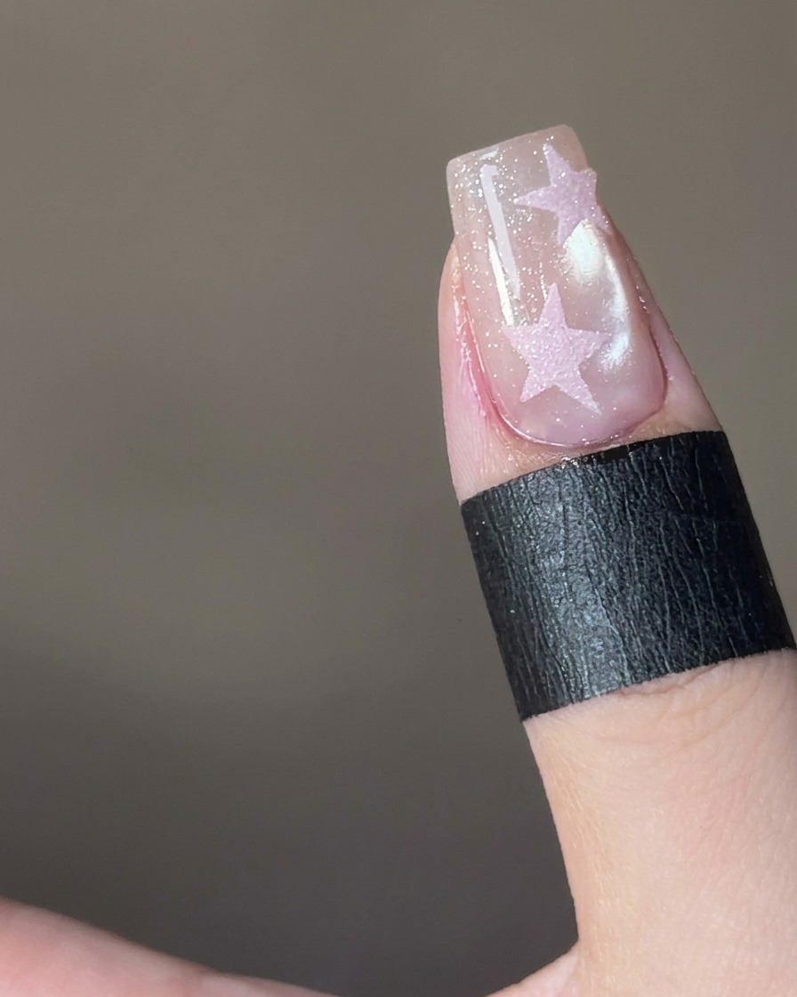 Tweezers gently lifting a star sticker off the nail to reveal the design.