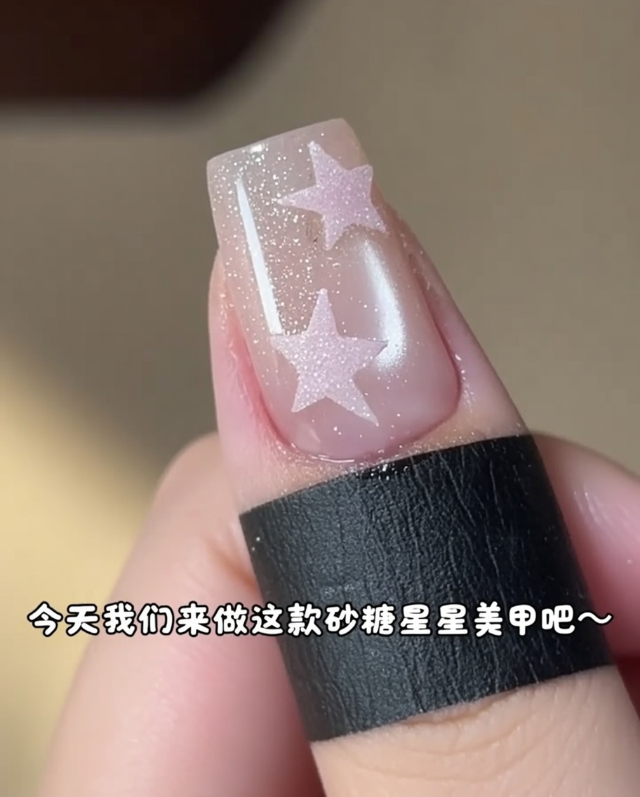 A small brush applying pink gel inside a star sticker on a nail.