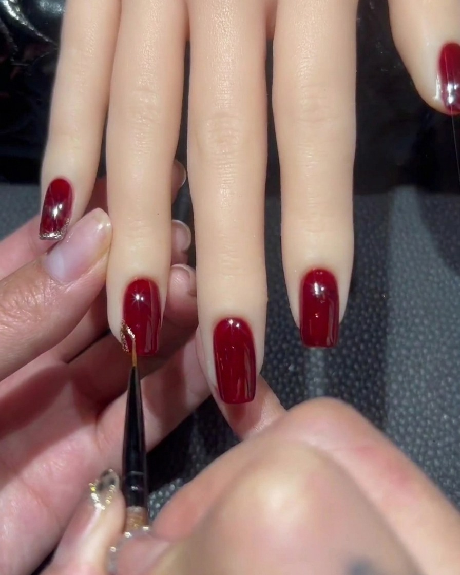 A fine liner brush picking up a bead of dense rose-gold glitter gel polish.
