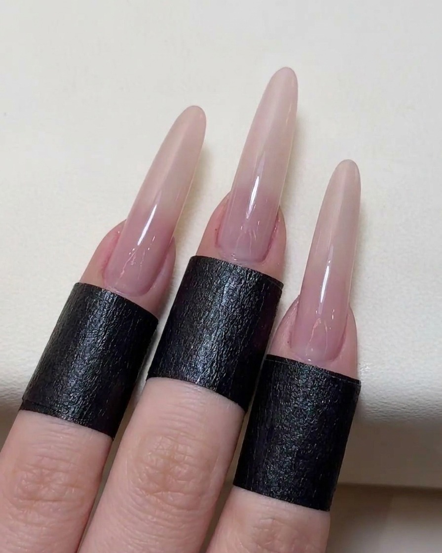 A pair of tweezers placing a delicate rose-shaped stencil sticker onto the center of the nude-colored nail.